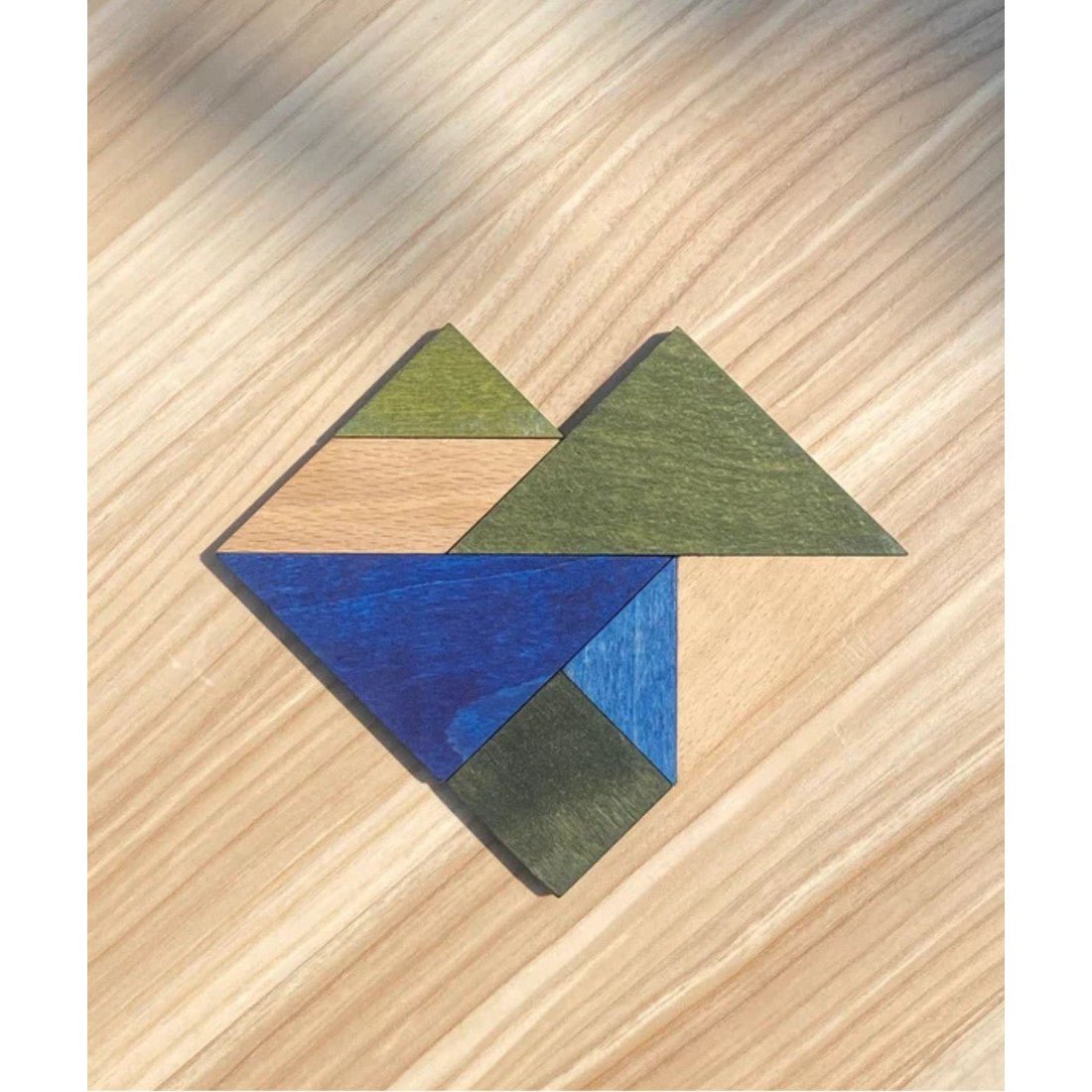 Wooden Storys tangrambitar i kalla färger lagda som en geometrisk figur
