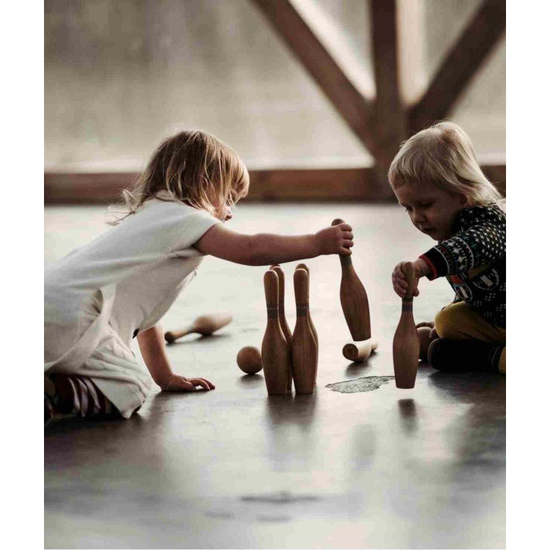 Två barn ställer upp Wooden Storys bowlingkäglor i trä på golvet
