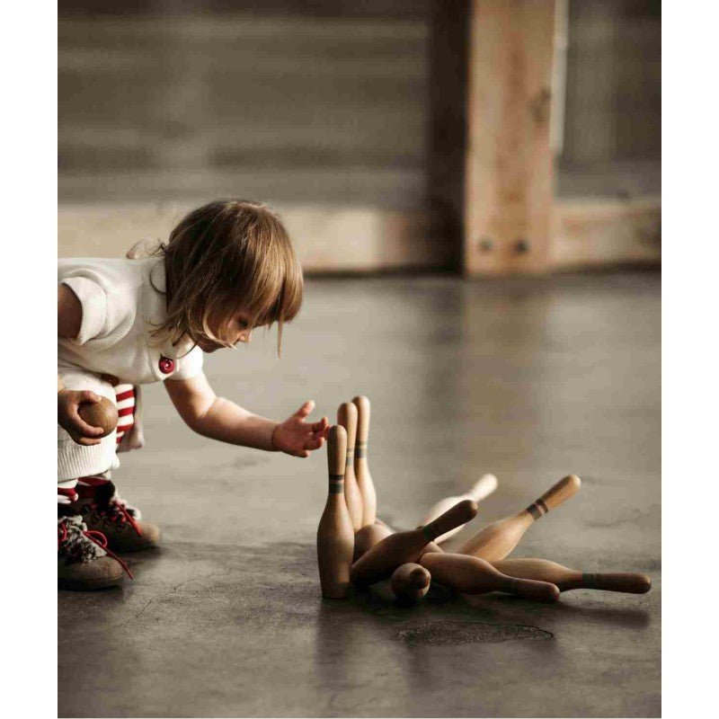 Barn leker med naturfärgade bowlingkäglor och klot från Wooden Story